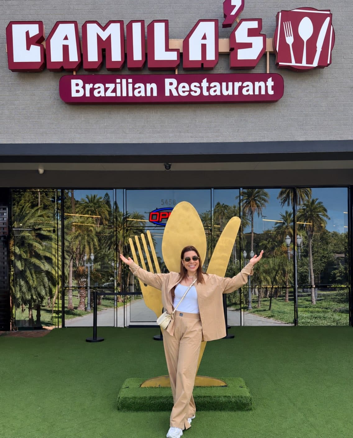 Visitante de braços abertos no pátio, com o garfo dourado atrás